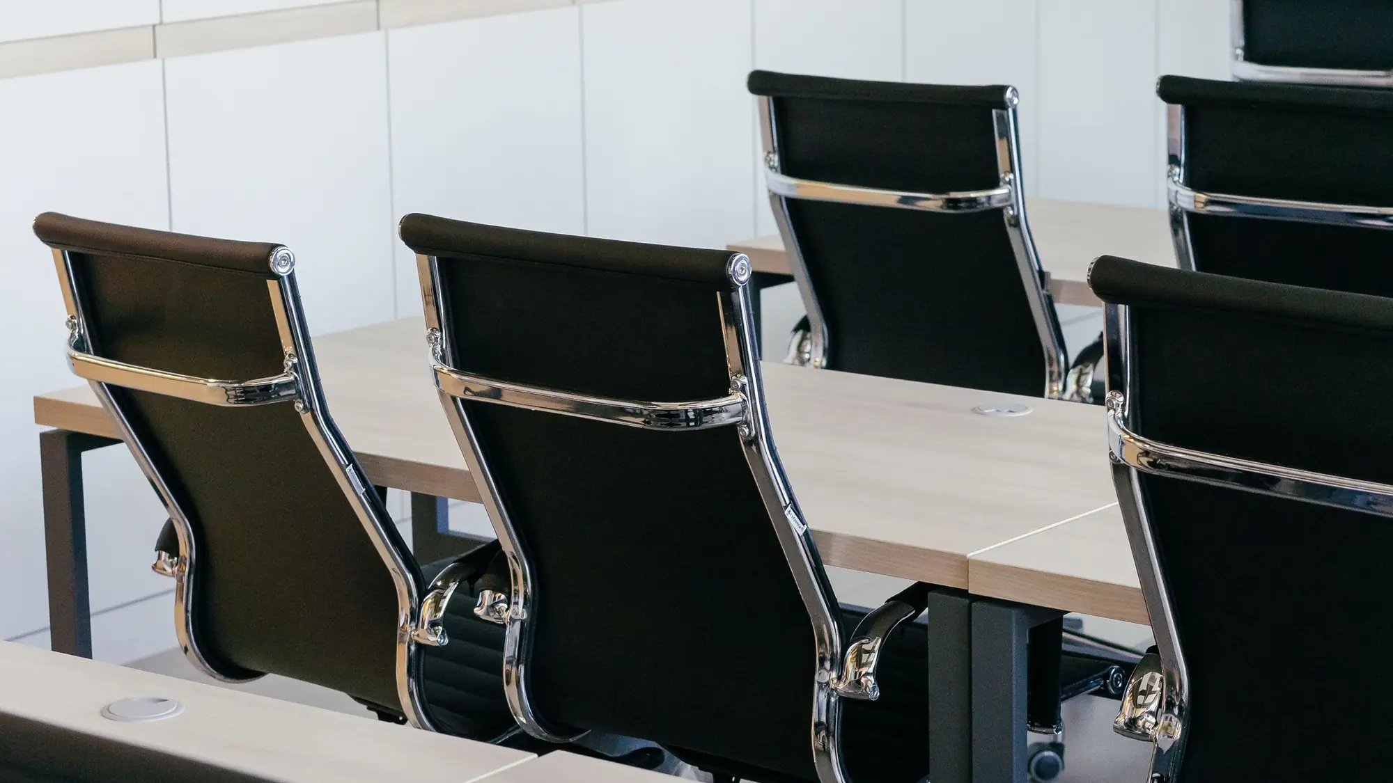 Sala de reuniones ordenada con mesas claras y sillas negras