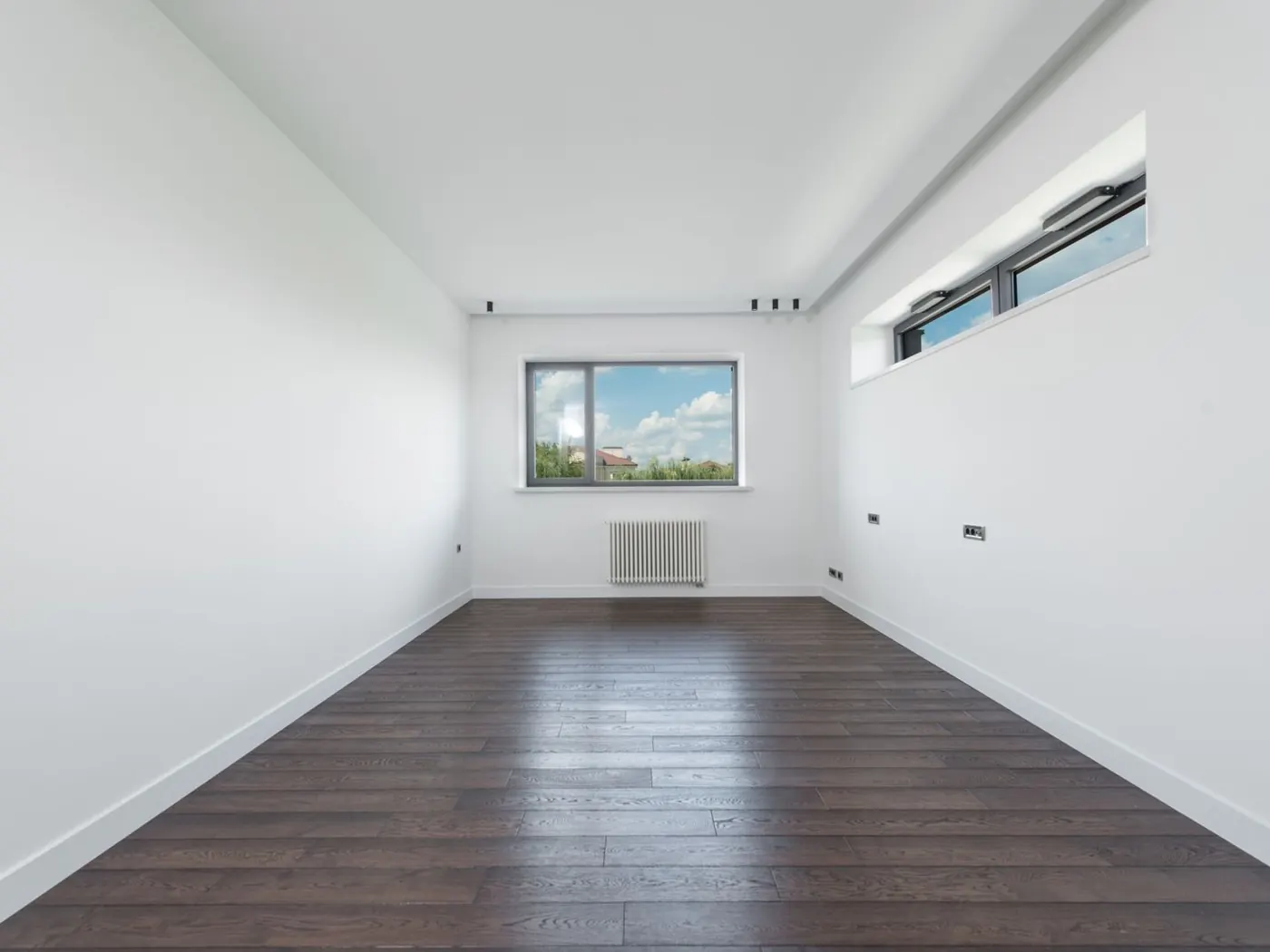 Habitación vacía de una vivienda, con las paredes blancas y el suelo de madera