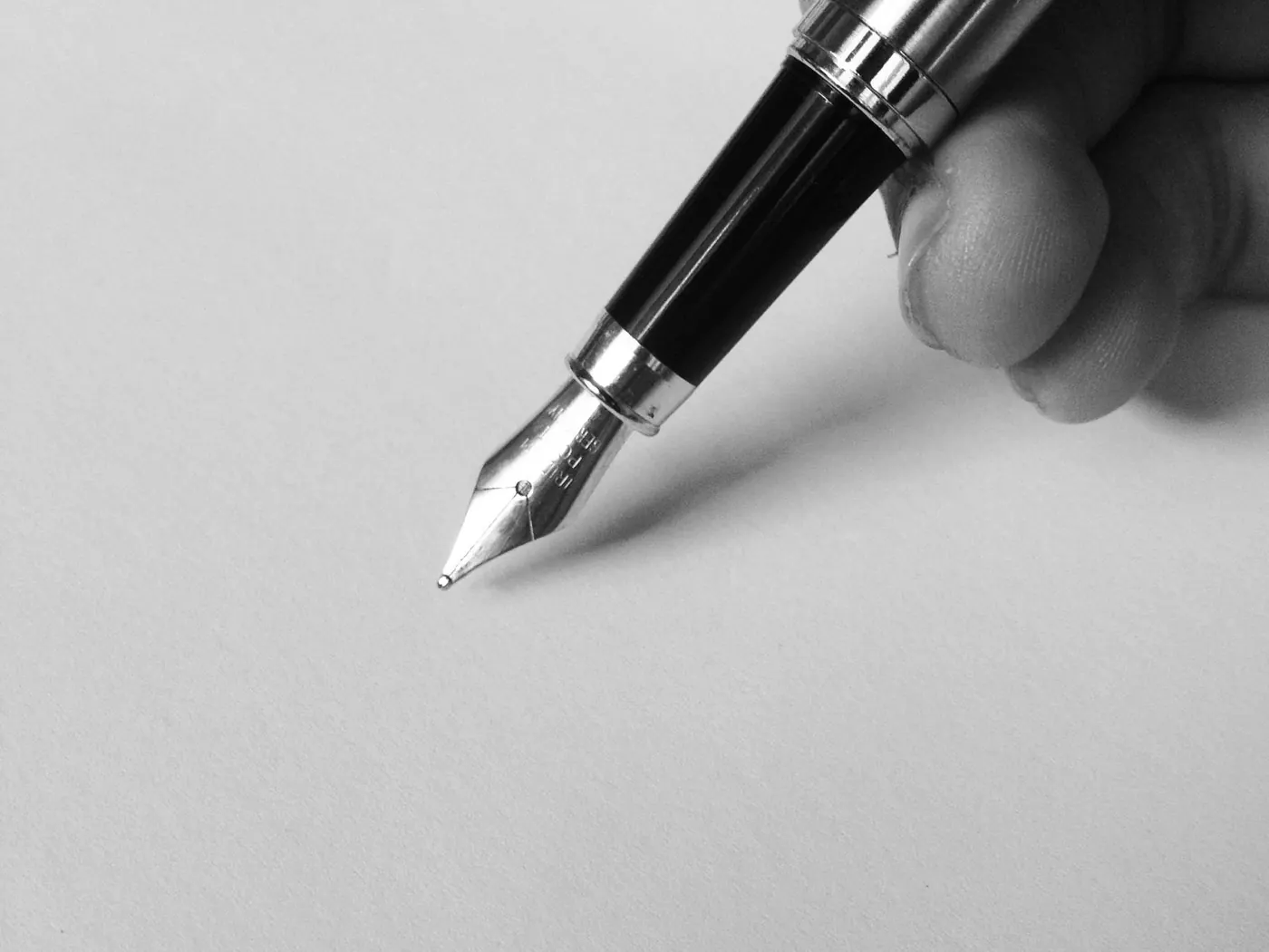 Mano con una pluma estilográfica a punto de escribir sobre un folio en blanco